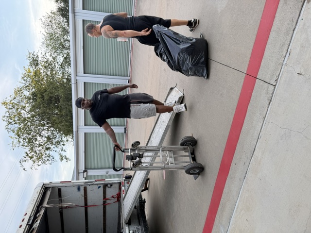 Two people loading items into a moving truck at a storage facility