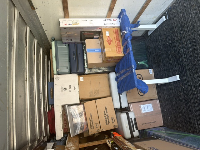Interior of moving truck loaded with cardboard boxes, furniture, and blue padding blankets