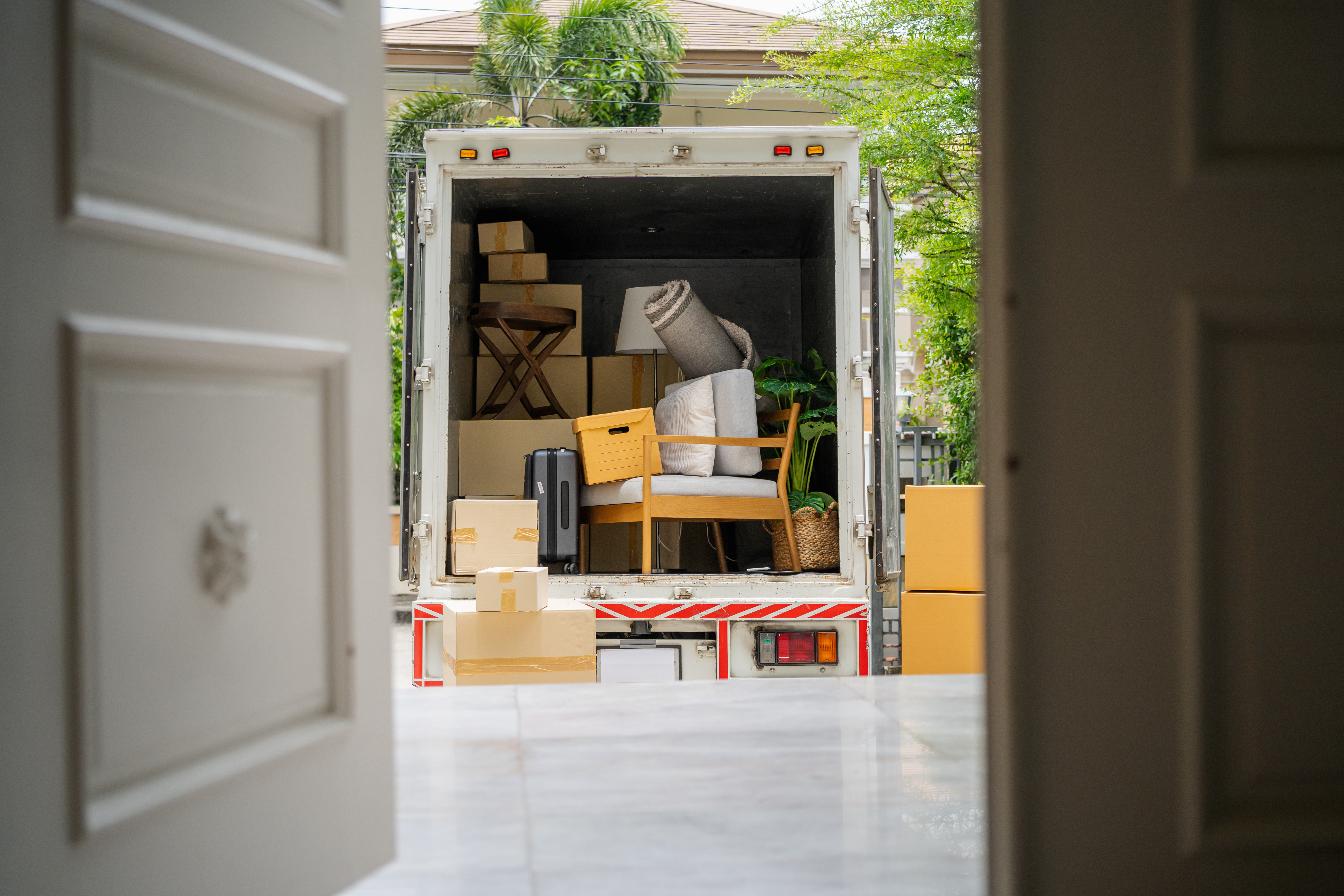 Moving truck loaded with furniture, boxes, and household items parked in a driveway